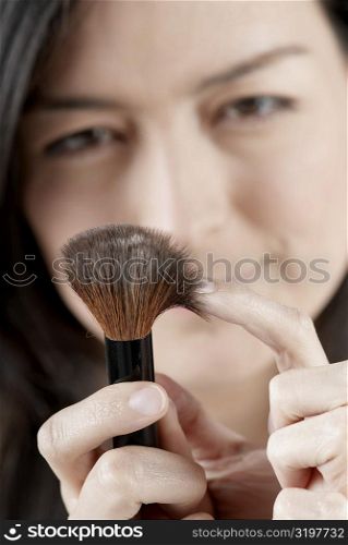 Portrait of a young woman holding a blush brush