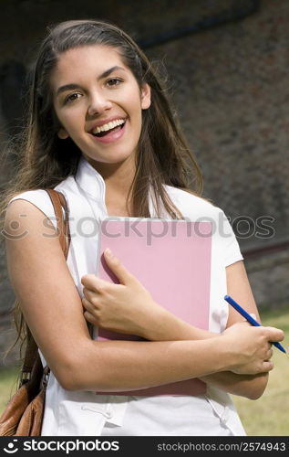 Portrait of a young woman holding a book and smiling