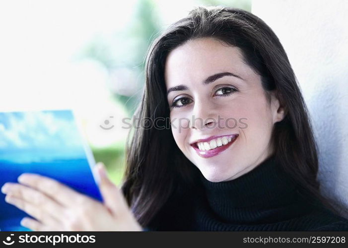 Portrait of a young woman holding a book and smiling