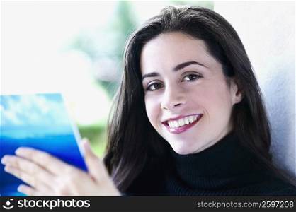 Portrait of a young woman holding a book and smiling