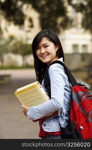 Portrait of a young woman holding a book and smiling