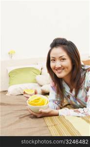 Portrait of a young woman holding a bowl of lemon slices and smiling