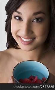 Portrait of a young woman holding a bowl of water with floating leaves