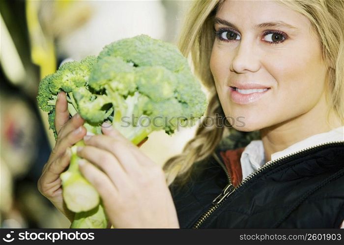 Portrait of a young woman holding a broccoli