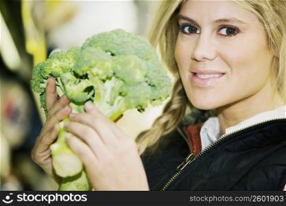 Portrait of a young woman holding a broccoli