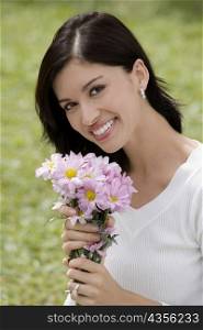 Portrait of a young woman holding a bunch of flowers and smiling
