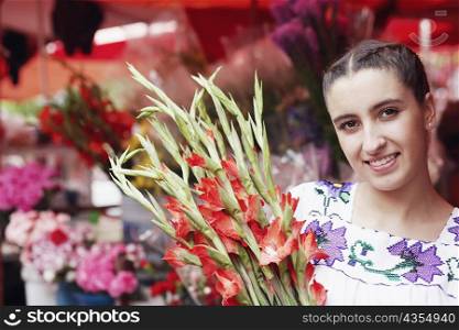 Portrait of a young woman holding a bunch of gladiolus