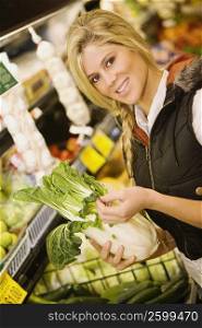 Portrait of a young woman holding a Chinese cabbage in a supermarket