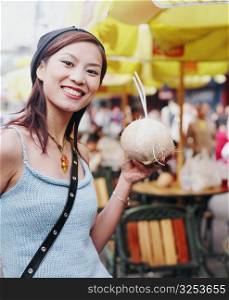 Portrait of a young woman holding a coconut drink