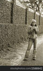 Portrait of a young woman holding a coffee cup and standing on the roadside
