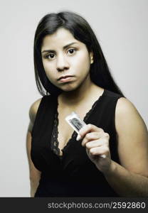 Portrait of a young woman holding a condom