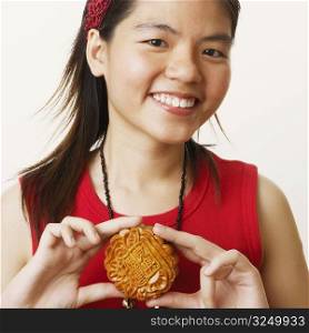 Portrait of a young woman holding a cookie and smiling
