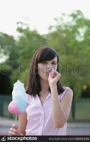 Portrait of a young woman holding a cotton candy and sucking her thumb