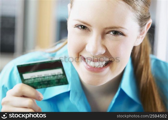 Portrait of a young woman holding a credit card and smiling