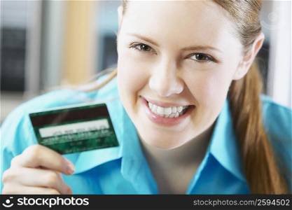 Portrait of a young woman holding a credit card and smiling