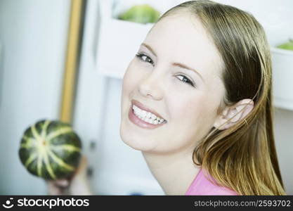 Portrait of a young woman holding a cucumber and smiling