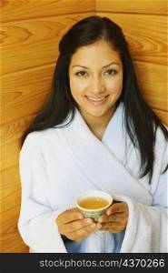 Portrait of a young woman holding a cup of aromatherapy oil and smiling