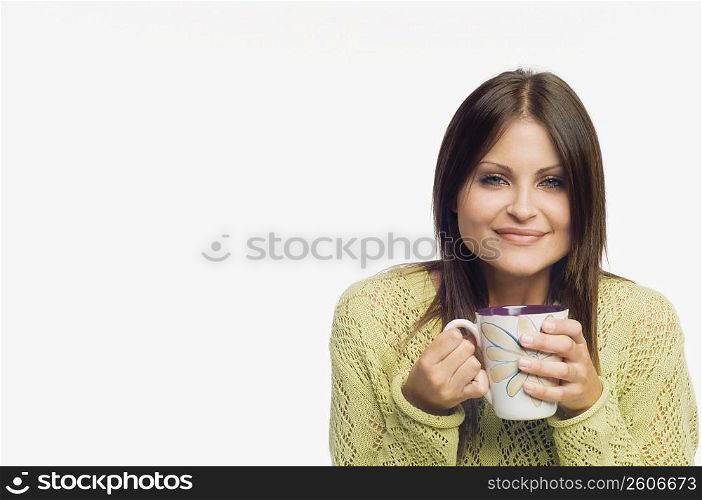 Portrait of a young woman holding a cup of coffee and smiling