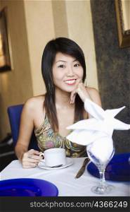Portrait of a young woman holding a cup of coffee in a restaurant