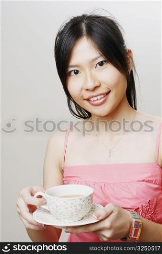 Portrait of a young woman holding a cup of tea and smiling