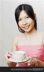Portrait of a young woman holding a cup of tea and smiling