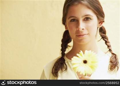 Portrait of a young woman holding a daisy flower