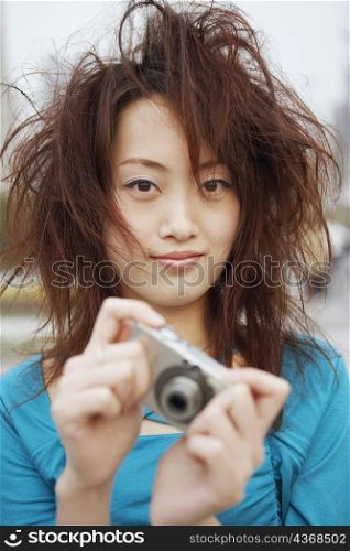 Portrait of a young woman holding a digital camera