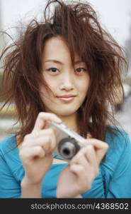 Portrait of a young woman holding a digital camera