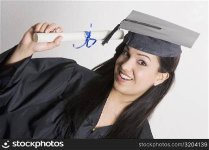 Portrait of a young woman holding a diploma and smiling