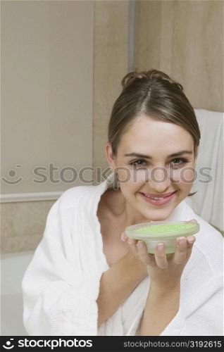 Portrait of a young woman holding a dish of bath crystals