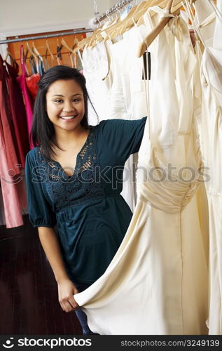 Portrait of a young woman holding a dress in a clothing store