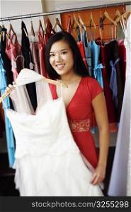 Portrait of a young woman holding a dress in a clothing store