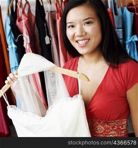 Portrait of a young woman holding a dress in a clothing store