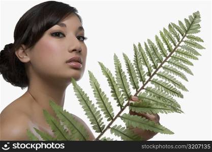 Portrait of a young woman holding a fern