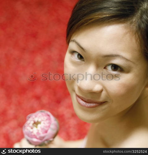 Portrait of a young woman holding a flower and smiling