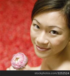 Portrait of a young woman holding a flower and smiling