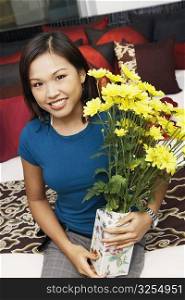Portrait of a young woman holding a flower vase and smiling