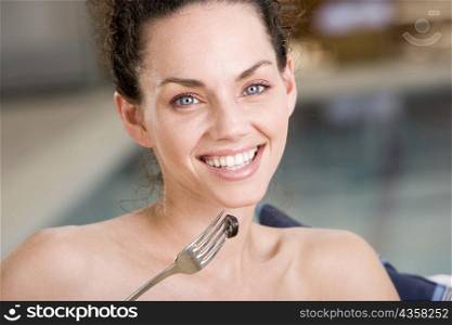 Portrait of a young woman holding a fork with an olive