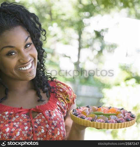 Portrait of a young woman holding a fruit tart