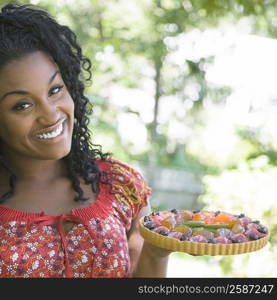 Portrait of a young woman holding a fruit tart