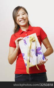 Portrait of a young woman holding a gift and looking cheerful