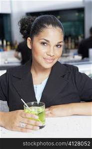 Portrait of a young woman holding a glass of cocktail