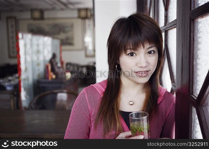 Portrait of a young woman holding a glass of herbal drink