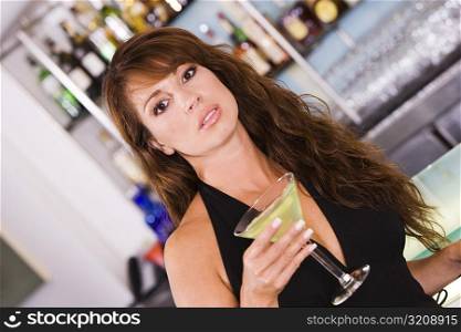 Portrait of a young woman holding a glass of martini