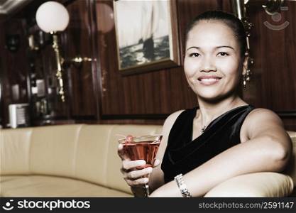 Portrait of a young woman holding a glass of martini and smiling