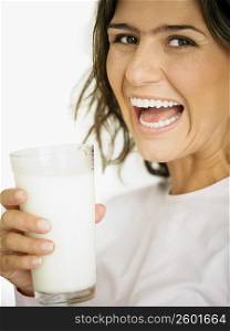 Portrait of a young woman holding a glass of milk and laughing