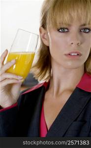 Portrait of a young woman holding a glass of orange juice