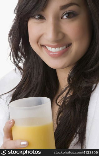 Portrait of a young woman holding a glass of orange juice and smiling