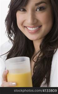 Portrait of a young woman holding a glass of orange juice and smiling