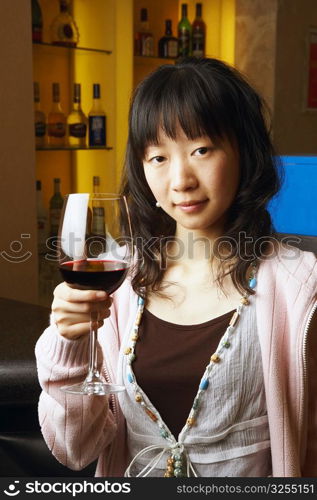 Portrait of a young woman holding a glass of red wine